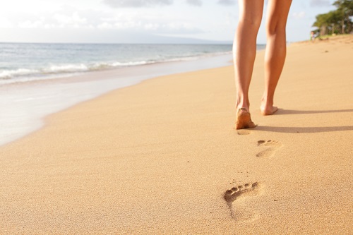 Beach travel - woman walking on sand beach closeup