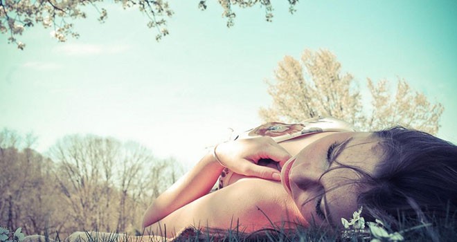 Mulher deitada em um parque pensando na influência de suas emoções em seus sonhos