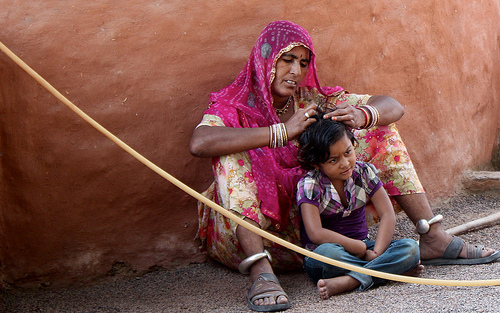 Mulher catando piolhos na cabeça de uma criança