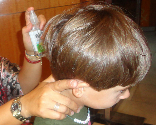 Mulher aplicando remédio de piolho no cabelo do filho