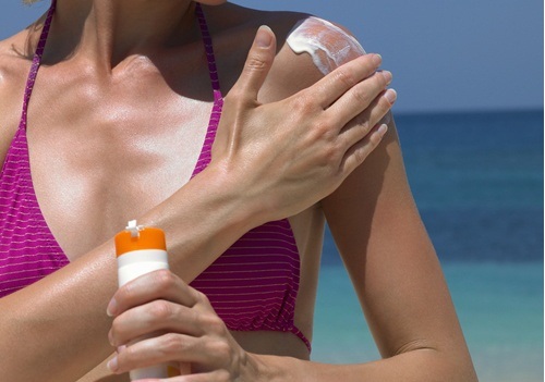Mulher colocando protetor solar para evitar câncer de pele
