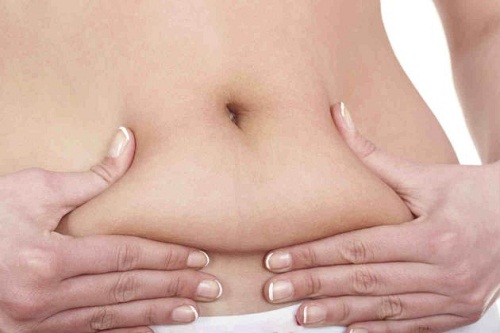 Mulher apertando gordura abdominal pensando em quantas calorias por dia ela pode perder
