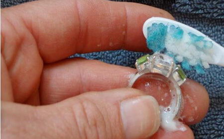 Pessoa limpando joia com pasta de dente