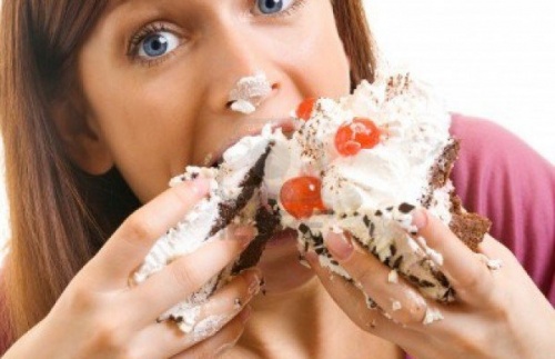 Mulher comendo bolo com gordura ou o açúcar
