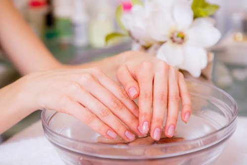Mulher molhando as mãos antes de fazer a manicure