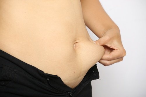 Mulher apertando a gordura porque quer diminuir a barriga