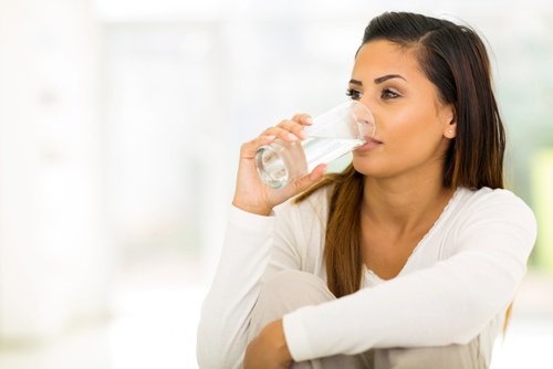 Mulher bebendo água para evitar infecção na bexiga