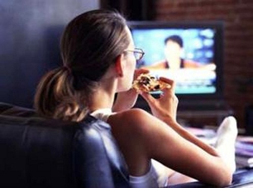 Comer-assistindo-televisao