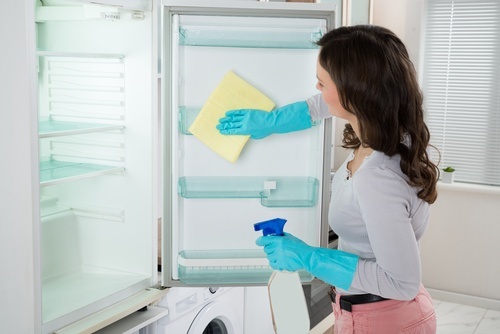 Mulher limpando a geladeira com produtos naturais