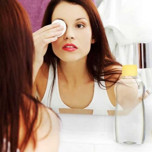 Mulher removendo maquiagem dos olhos com óleo para bebês