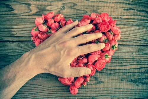 Homem põe a mão sobre coração de rosas