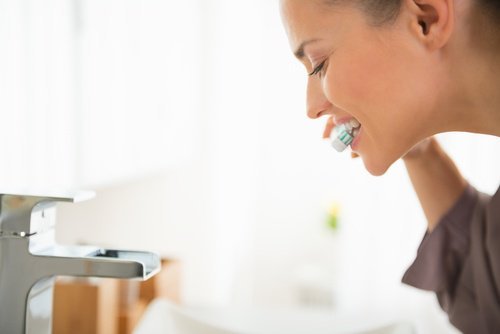 Mulher branqueando os dentes com água oxigenada
