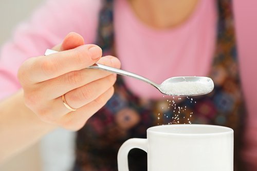 Mulher adicionando açúcar ao café