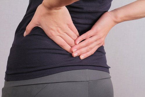 Mulher com dor na coluna vertebral na altura da lombar