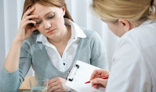 Mulher com dor de cabeça conversando com médica