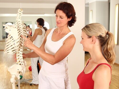 Mulher mostrando a coluna vertebral de um esqueleto para a outra