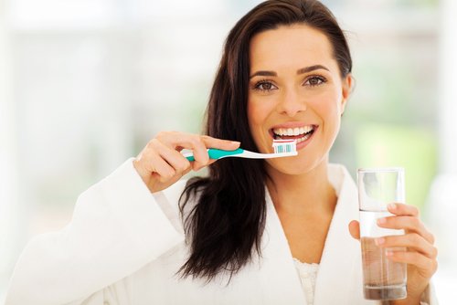 Mulher escovando os dentes com a mão não util para evitar Alzheimer