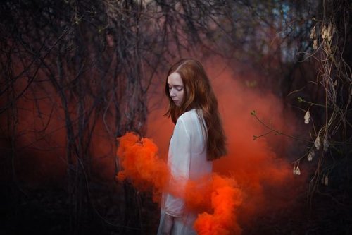 Mulher rodeada de fumaça vermelha