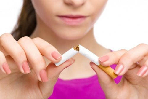 Mulher que deixou de fumar e quebra o cigarro