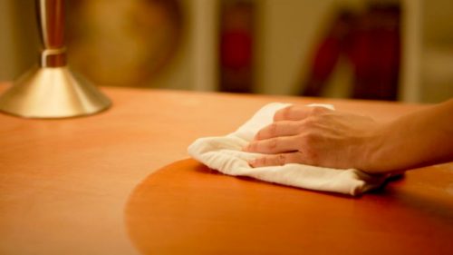 Pessoa passando óle de bacalhau para eliminar arranhões na madeira