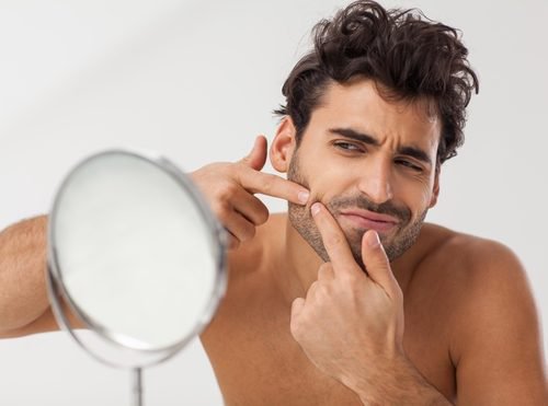 Homem espremendo espinha. Isso deveria ser evitado com o uso de Vick Vaporub