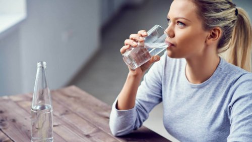 Mulher bebendo água para evitar a má circulação nas pernas