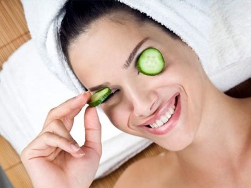 Mulher com rodelas de pepinos nos olhos