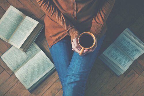 Mulher com uma xícara de café no meio de livros