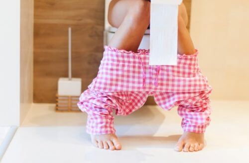 Mulher no banheiro com rolo de papel higiênico