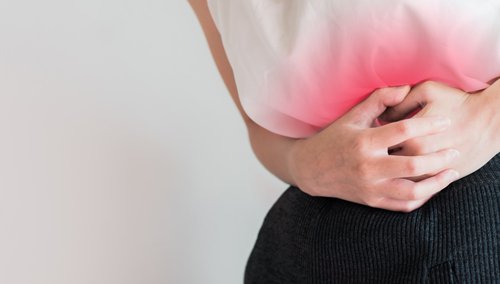 Mulher segurando o ventre sentido dores ou distúrbios menstruais