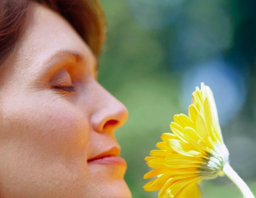 Mulher sentindo aroma de flor