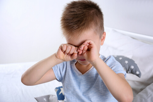 Menino com Síndrome de Asperger acordando, esfregando os olhos