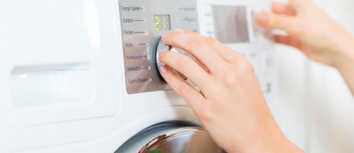 Mulher escolhendo o tipo de lavagem na máquina de lavar