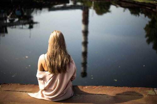 Mulher sentada ao lado de lago