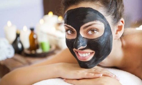 Mulher com máscara negra no rosto para eliminar os cravos e impurezas