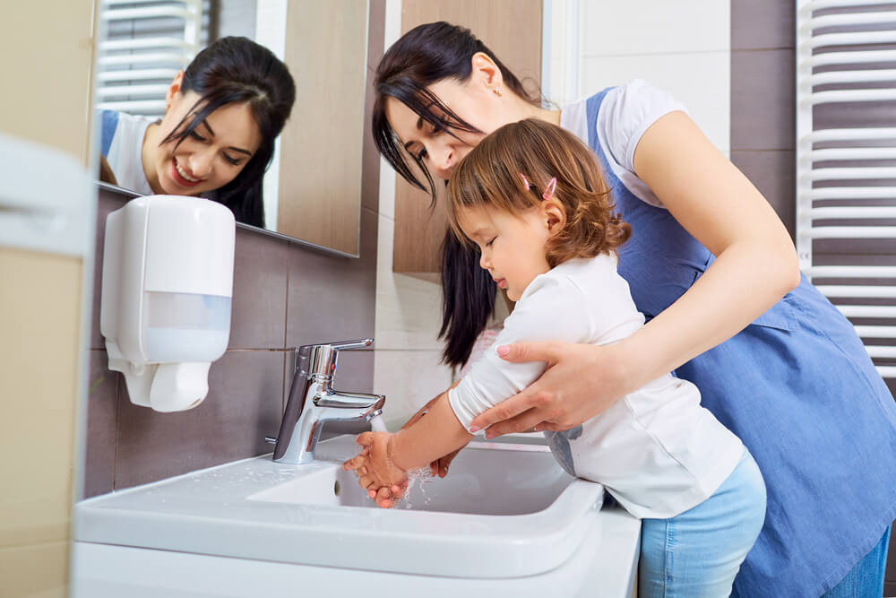 Mãe ensinando filha a lavar as mãos