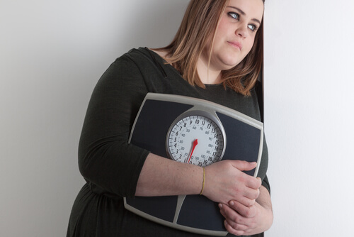 Mulher com sobrepeso segurando uma balança