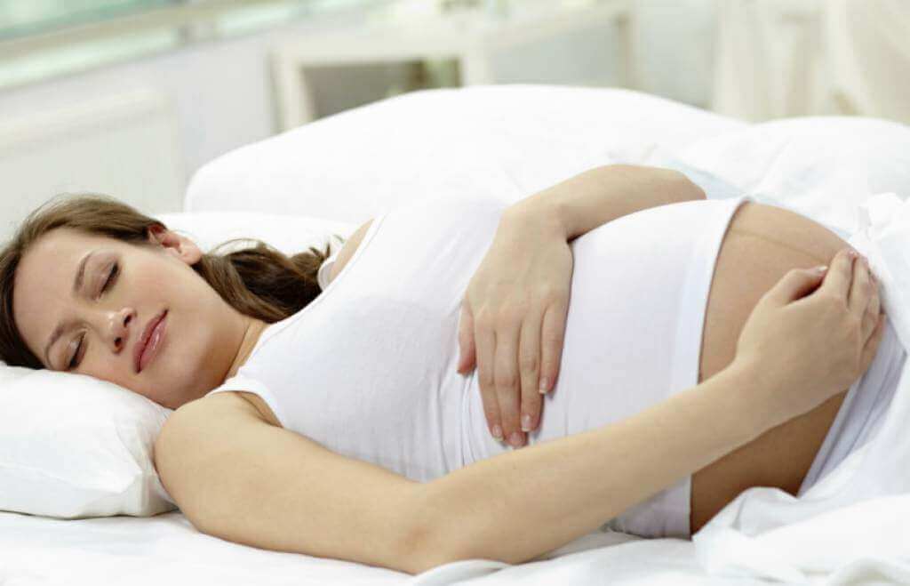 Mulher grávida deitada na cama