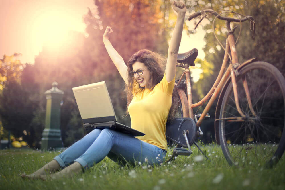 Mulher feliz diante de seu notebook