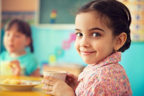Menina sorrindo e comendo