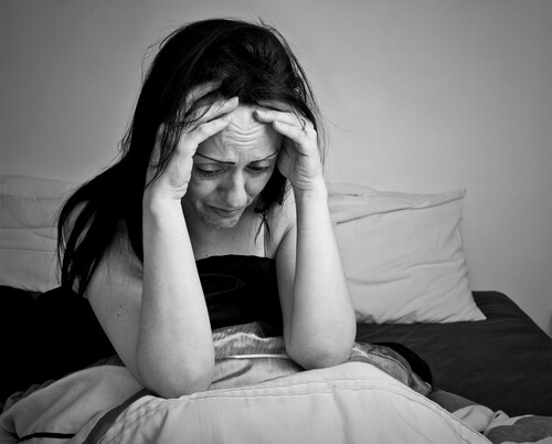 Mulher com ataque de pânico sentada na cama