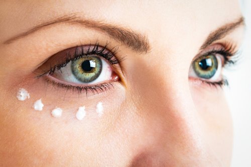 Mulher usando cápsula de vitamina como creme para os olhos