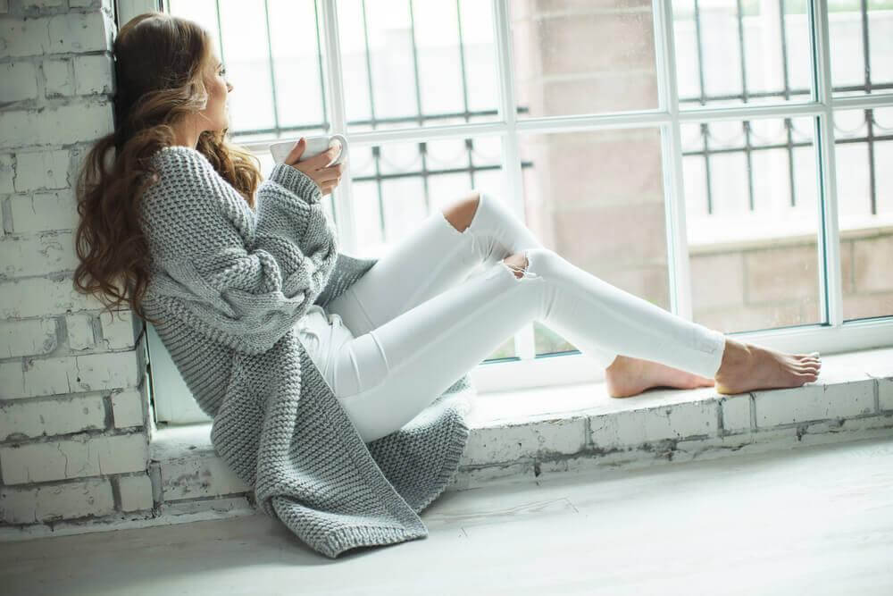 Mulher tomando café na janela