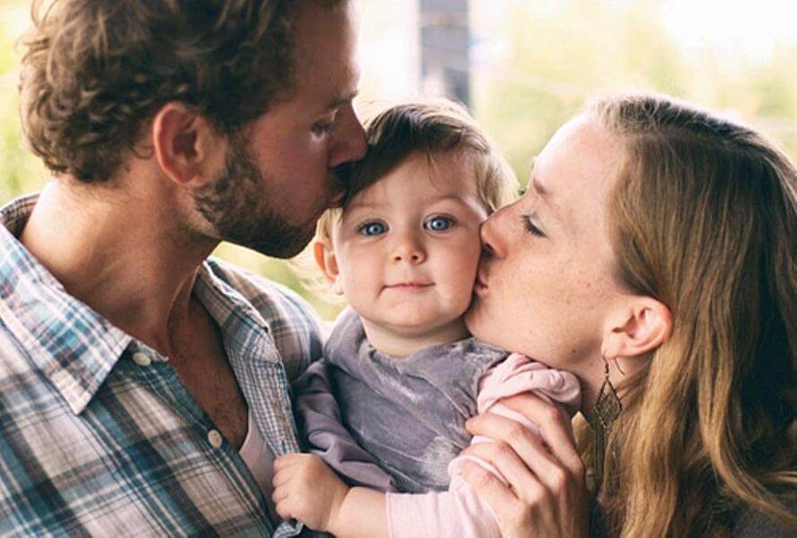 Pais beijando sua filha pequena