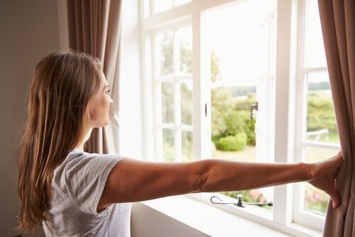 Mulher abrindo as cortinas