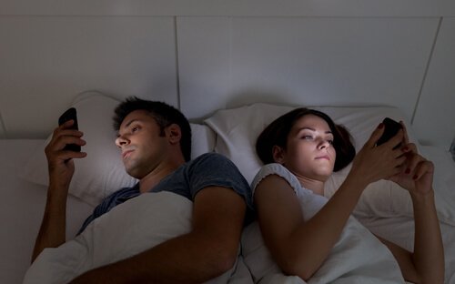 Casal usando o celular na cama