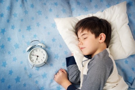 Menino dormindo ao lado do despertador