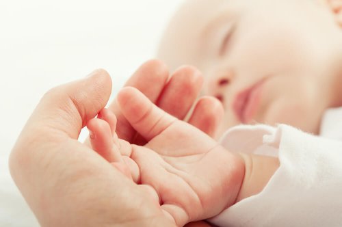 Mãe acariciando a mão de seu bebê