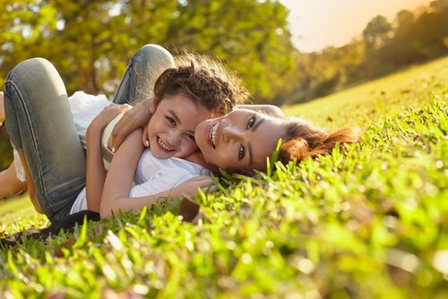 Mãe e filha abraçadas na grama
