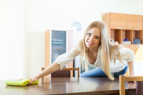 Mulher passando um pano para disfarçar arranhões na madeira